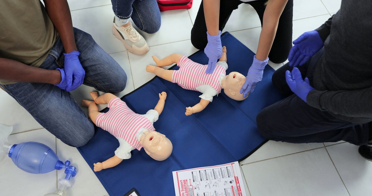 Group of People CPR First Aid Baby Training Course. Baby CPR Dummy First Aid Training.