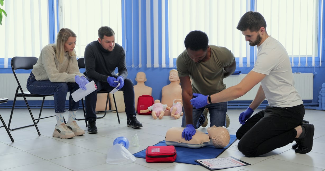 Group of people CPR First Aid Training course. CPR teen dummy first aid training.